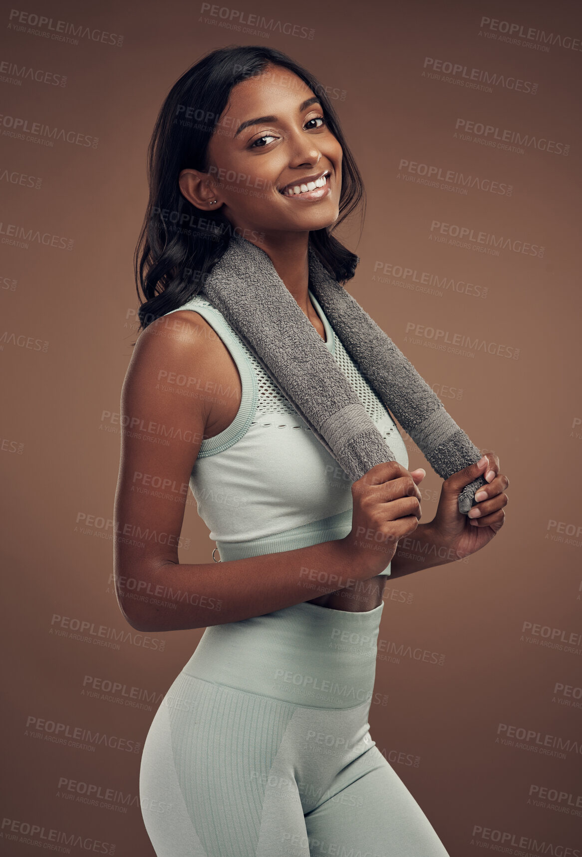 Buy stock photo Shot of an attractive young woman standing alone in the studio and posing with a towel after working out