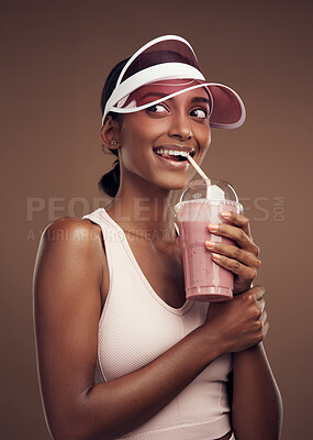 Buy stock photo Shot of an attractive young woman standing alone in the studio and drinking a smoothie