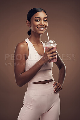 Buy stock photo Shot of an attractive young woman standing alone in the studio and drinking a smoothie