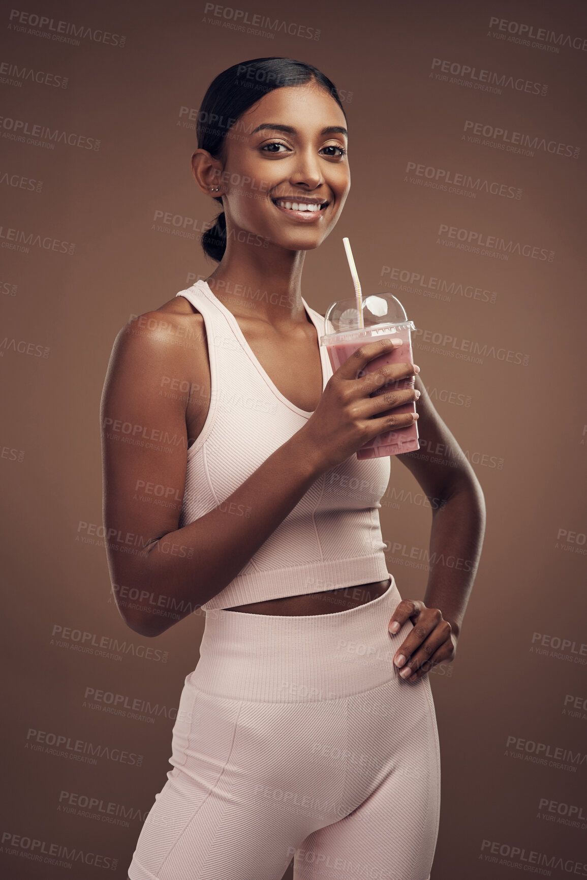 Buy stock photo Shot of an attractive young woman standing alone in the studio and drinking a smoothie