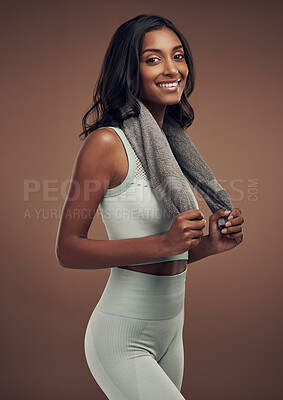 Buy stock photo Shot of an attractive young woman standing alone in the studio and posing with a towel after working out