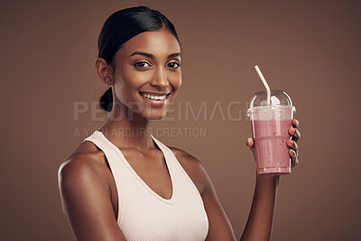 Buy stock photo Shot of an attractive young woman standing alone in the studio and drinking a smoothie