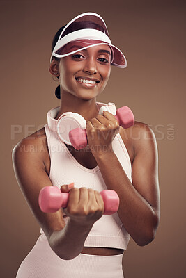 Buy stock photo Shot of an attractive young woman standing alone in the studio and using dumbbells while working out