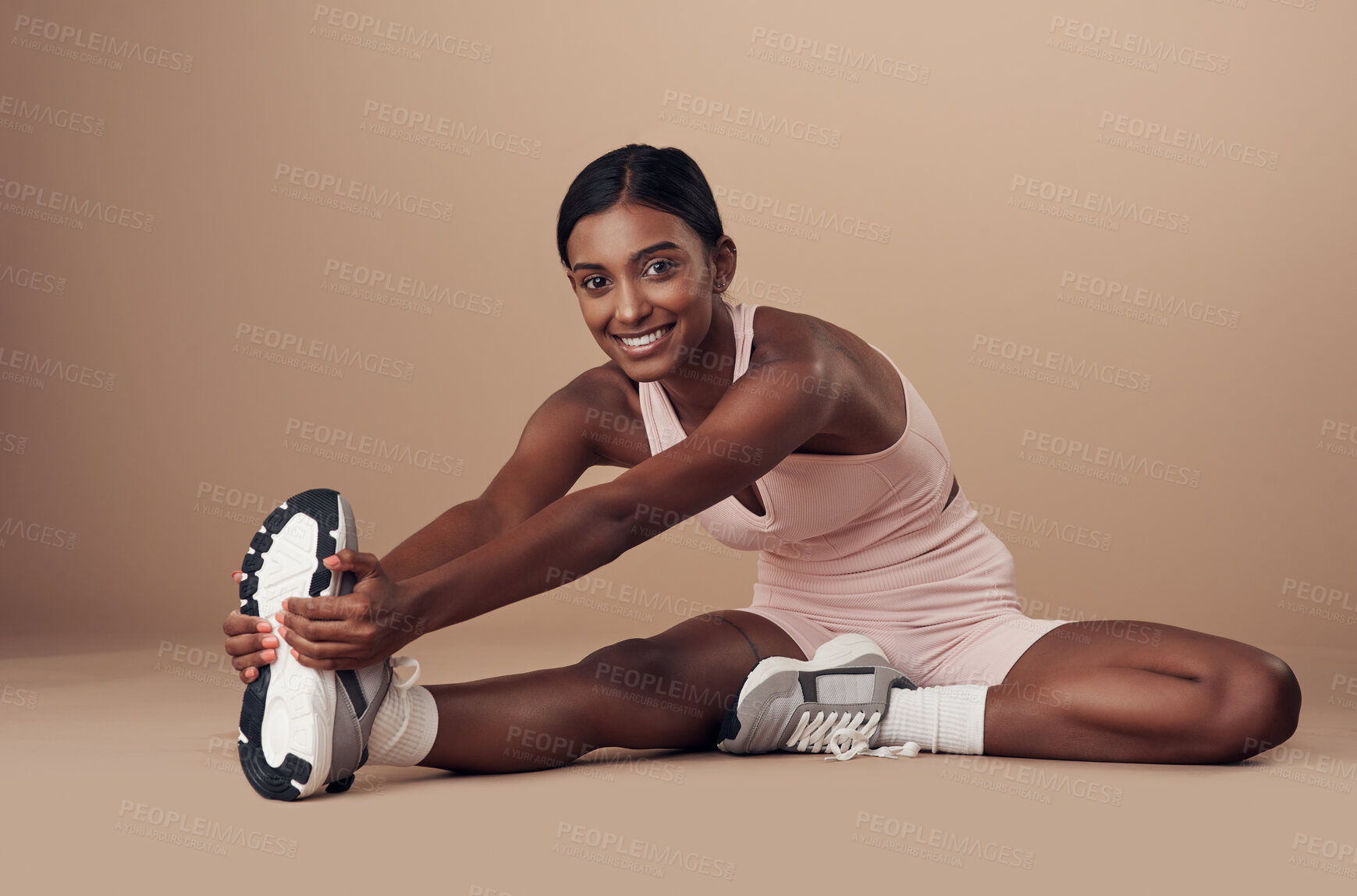 Buy stock photo Full length shot of an attractive young woman sitting alone in the studio and stretching before working out