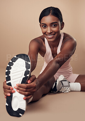 Buy stock photo Shot of an attractive young woman sitting alone in the studio and stretching before working out