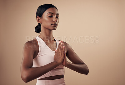 Buy stock photo Shot of an attractive young woman standing alone in the studio and holding a meditative pose while practising yoga
