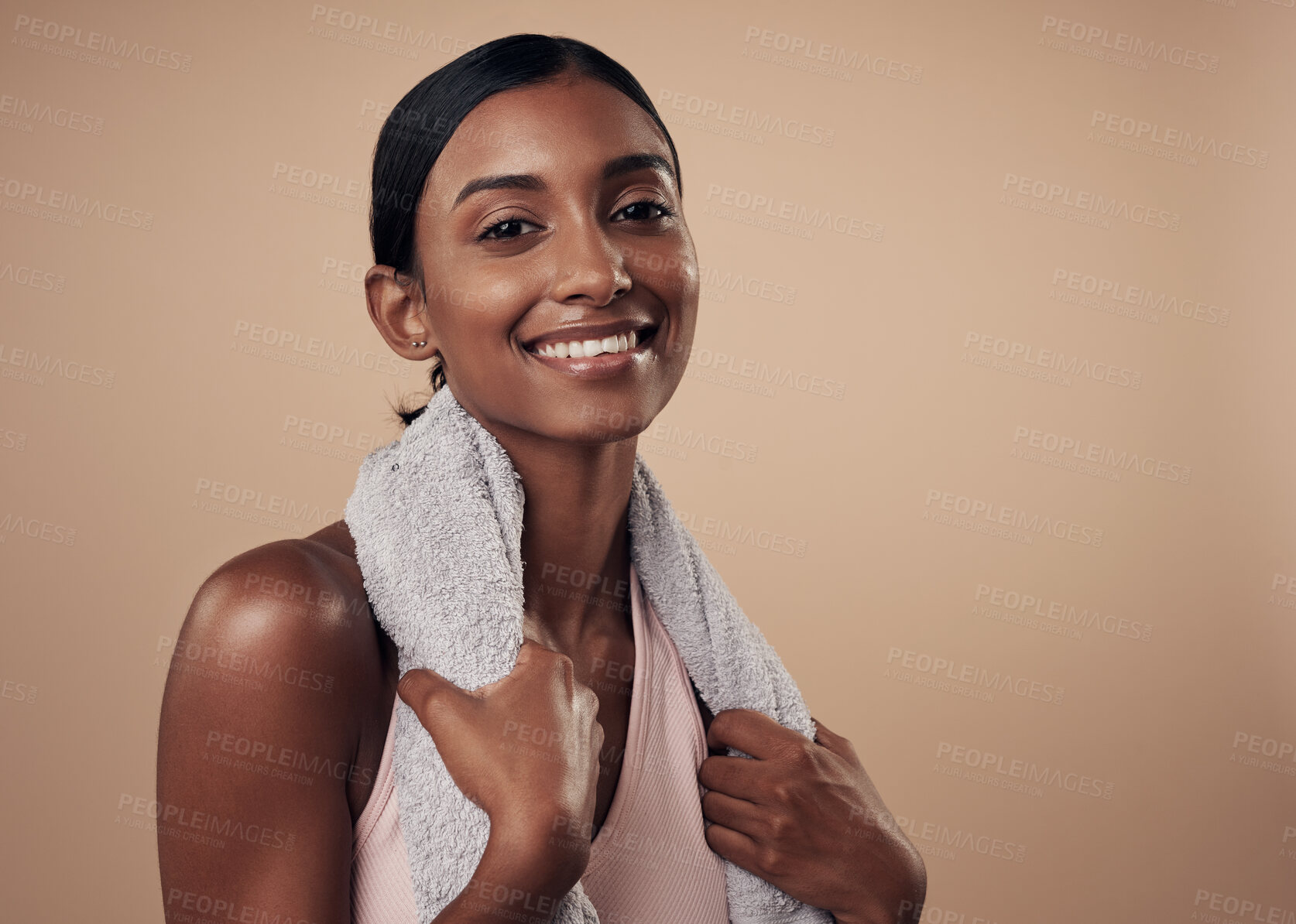 Buy stock photo Shot of an attractive young woman standing alone in the studio and posing with a towel after working out