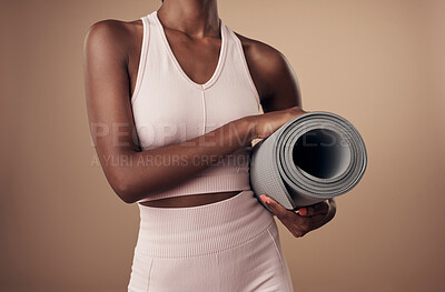 Buy stock photo Cropped shot of an unrecognizable woman standing alone in the studio and holding a yoga mat