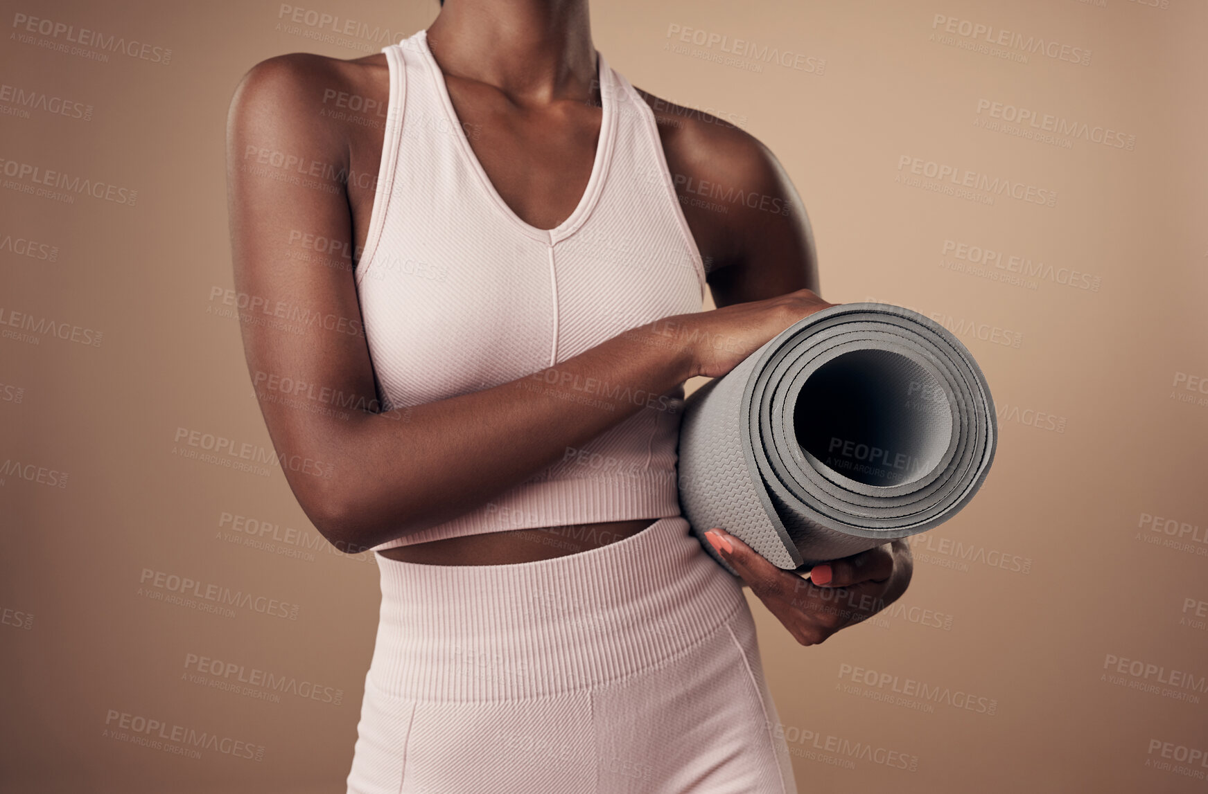 Buy stock photo Cropped shot of an unrecognizable woman standing alone in the studio and holding a yoga mat