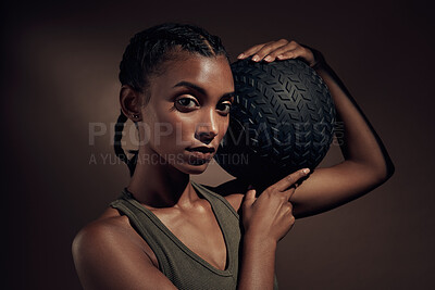 Buy stock photo Shot of an attractive young woman standing alone in the studio and holding a medicine ball while working out