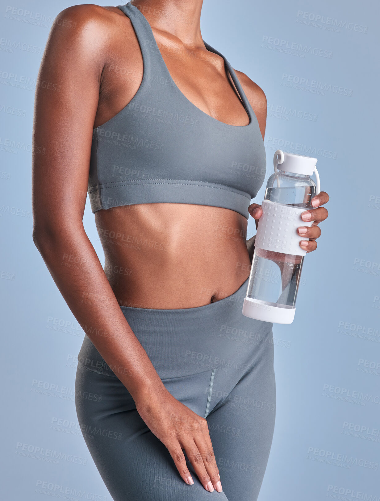 Buy stock photo Studio shot of a fit woman drinking bottled water against a grey background