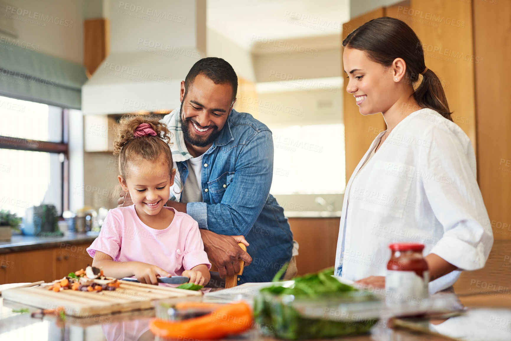 Buy stock photo Shot of a couple and their daughter cooking together in the kitchen at home