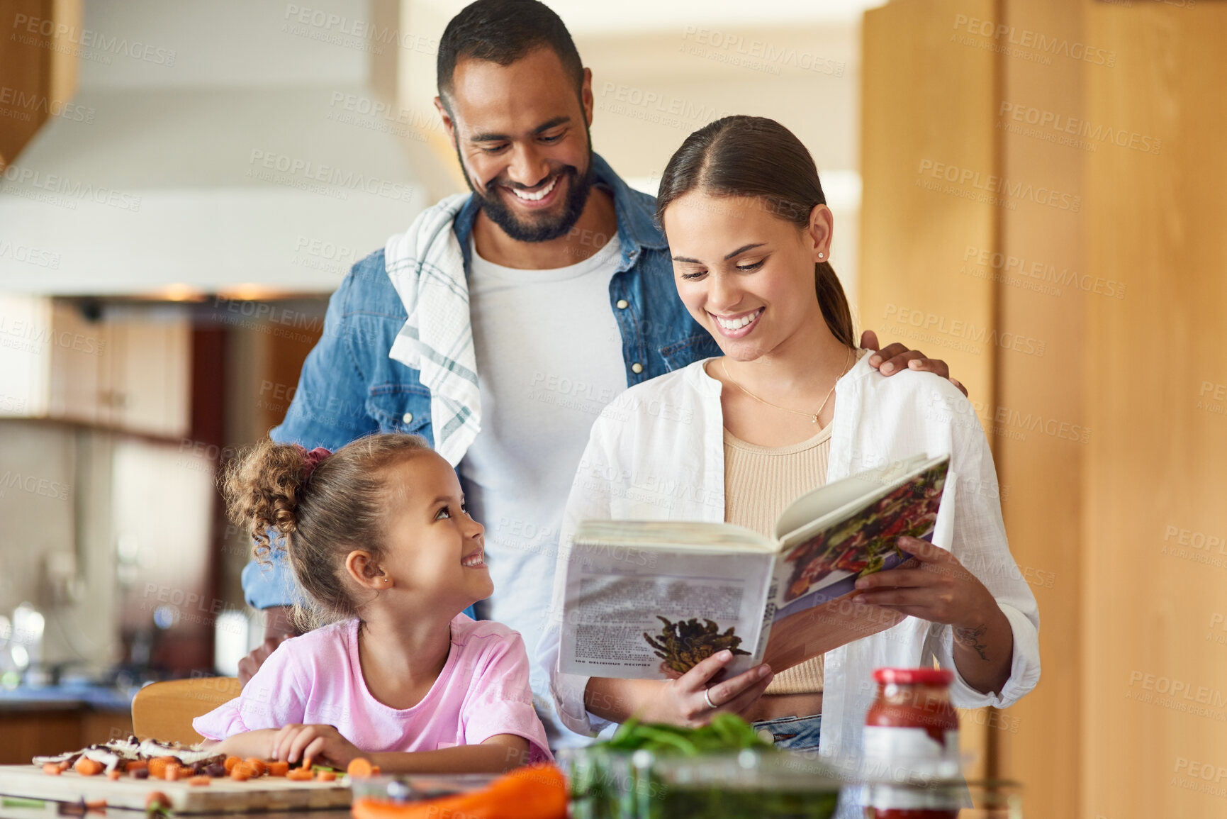 Buy stock photo Shot of a couple and their daughter cooking together in the kitchen at home