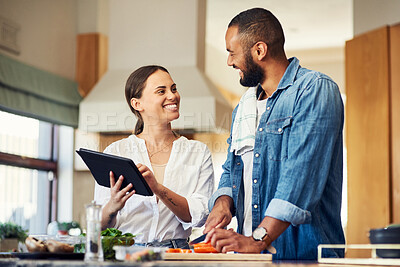 Buy stock photo Shot of a young couple using a digital tablet while cooking at home