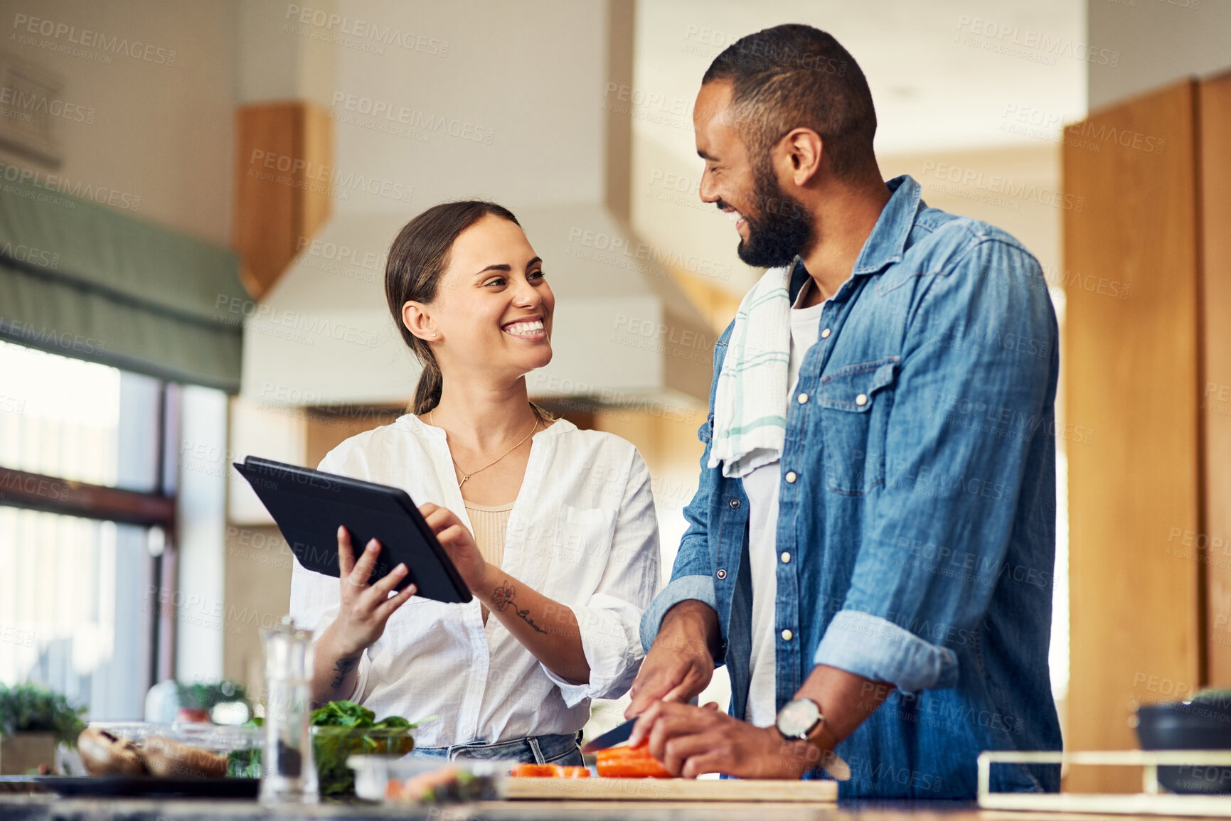 Buy stock photo Shot of a young couple using a digital tablet while cooking at home