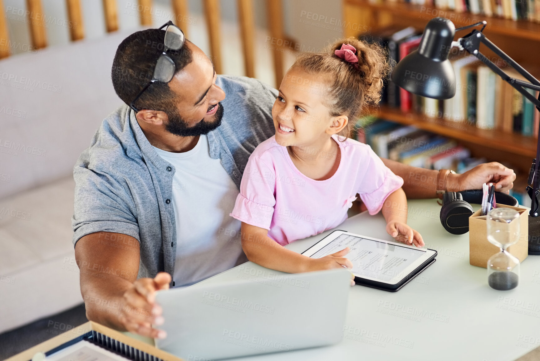 Buy stock photo Shot of a young father showing his daughter his work while she uses his digital tablet