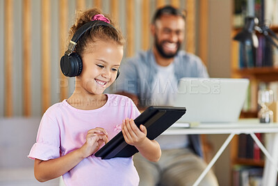 Buy stock photo Shot of a little girl using her fathers digital tablet while listening to music