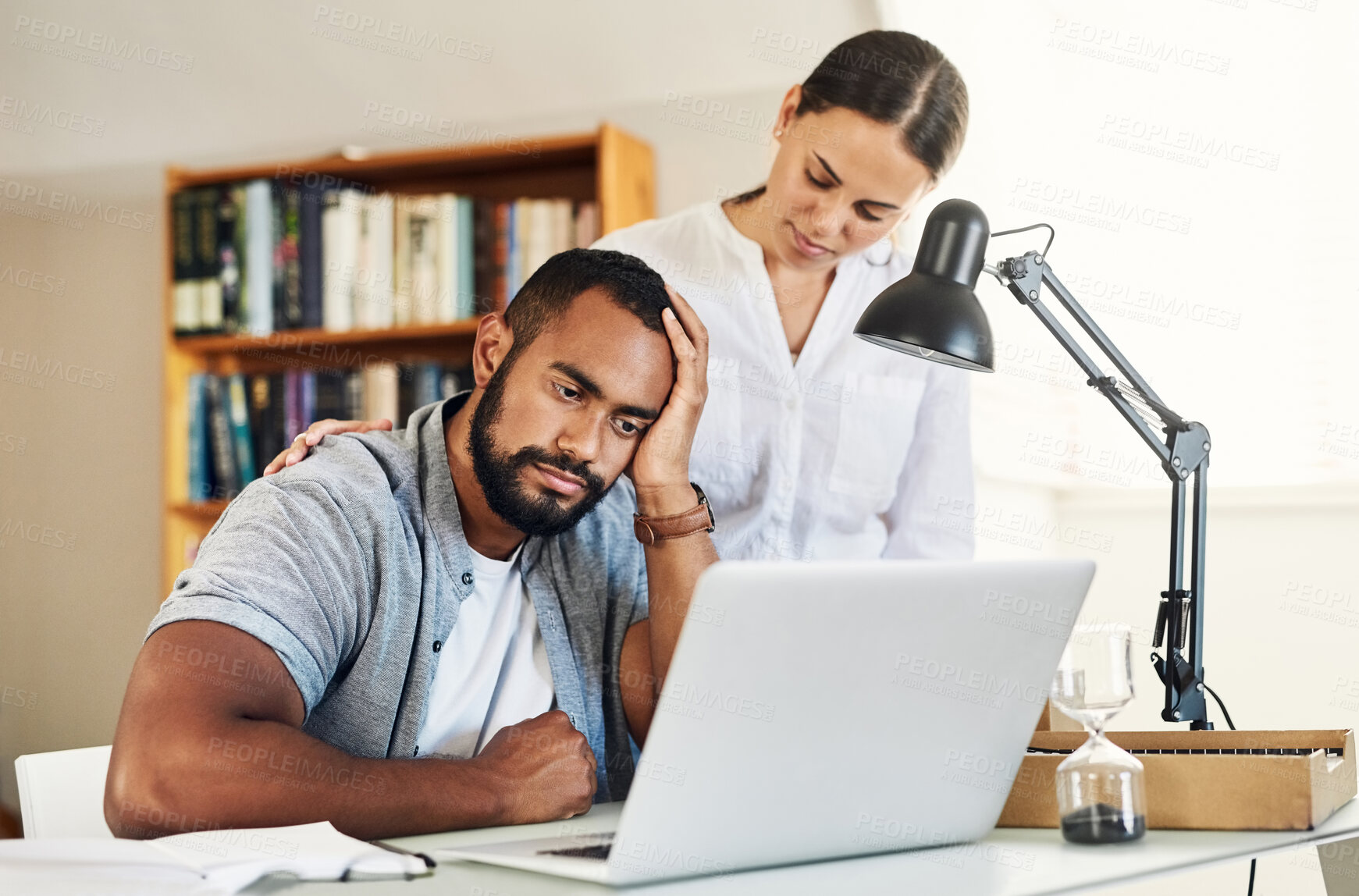 Buy stock photo Shot of a young woman comforting her husband while he works from home