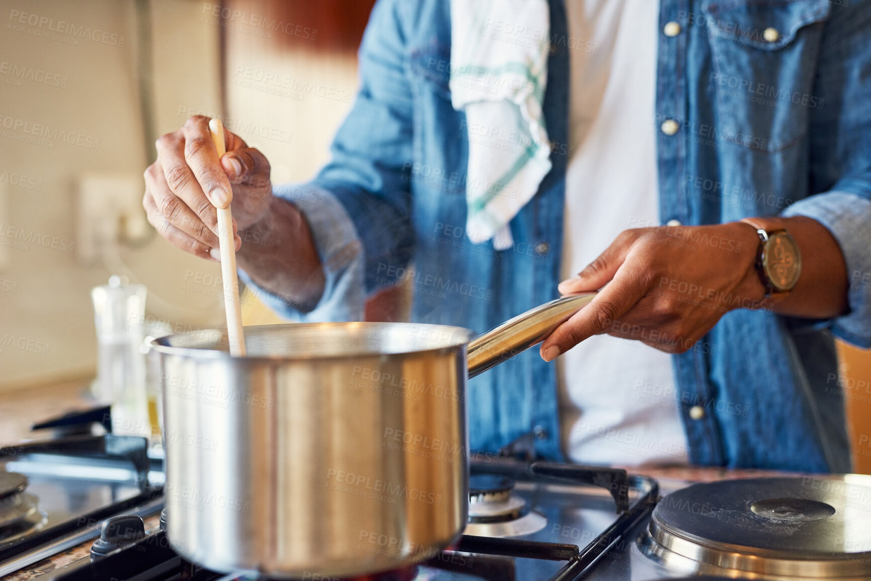 Buy stock photo Cropped shot of a young man stirring a pot in his kitchen at home