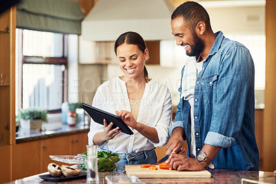 Buy stock photo Shot of a young couple using a digital tablet while cooking at home