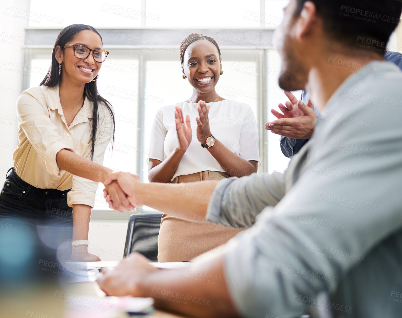 Buy stock photo Cropped shot of two young businesspeople shaking hands during a meeting in the boardroom