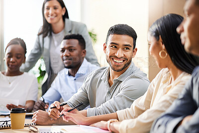 Buy stock photo Cropped shot of a handsome young businessman sitting with his colleagues in the boardroom during a meeting