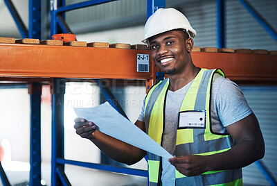 Buy stock photo Shot of a handsome young contractor standing in the warehouse and reading paperwork