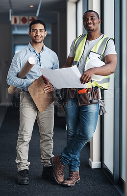 Buy stock photo Shot of two young architects standing together and having a discussion about the room before they renovate
