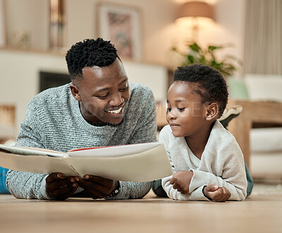 Buy stock photo Cropped shot of a handsome young man reading to his son while lying on the living room floor at home