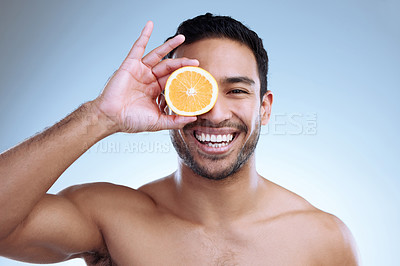 Buy stock photo Studio portrait of a handsome young man posing with an orange against a grey background
