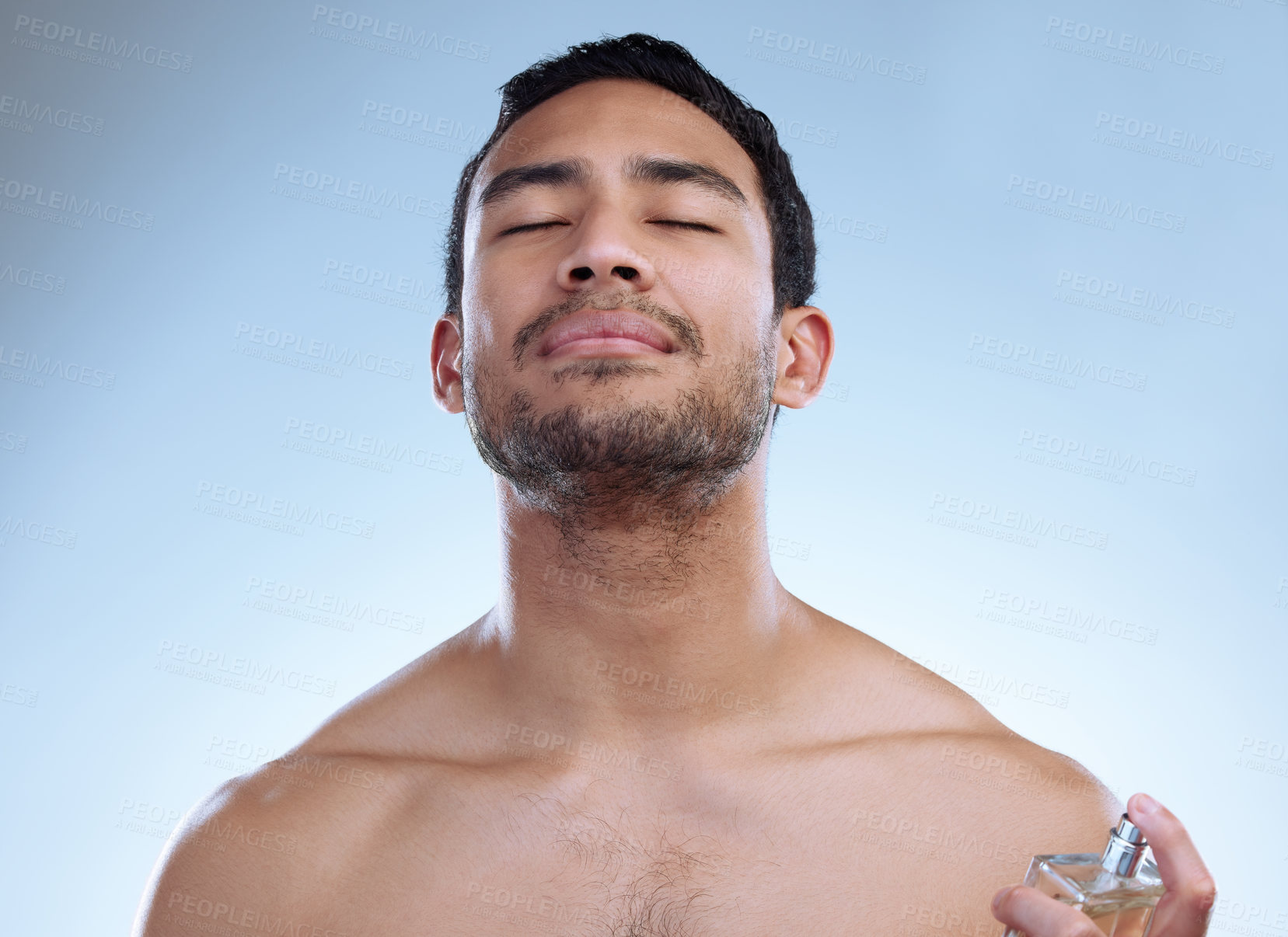 Buy stock photo Man, perfume and studio for skincare or smell, body care and clean scent on blue background. Male person, glass bottle and luxury product for grooming, mist and cologne or apply aroma for fragrance