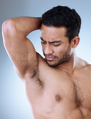 Buy stock photo Studio shot of a handsome young man smelling his armpit against a grey background