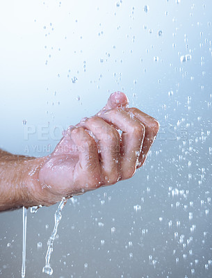 Buy stock photo Studio shot of an unrecognizable man holding his hand out under running water against a grey background