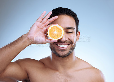 Buy stock photo Studio shot of a handsome young man posing with an orange against a grey background