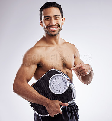 Buy stock photo Portrait, happy and man pointing with scale for fitness in studio for body care, wellness, health or diet for muscles. Male person, athlete or dietitian and smile for weight loss by white background