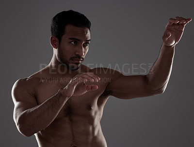 Buy stock photo Shot of a young man practicing his punches against a studio background