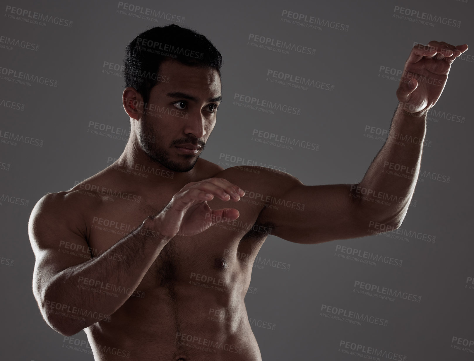 Buy stock photo Shot of a young man practicing his punches against a studio background