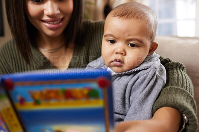 Buy stock photo Shot a mother reading a book to her baby at home