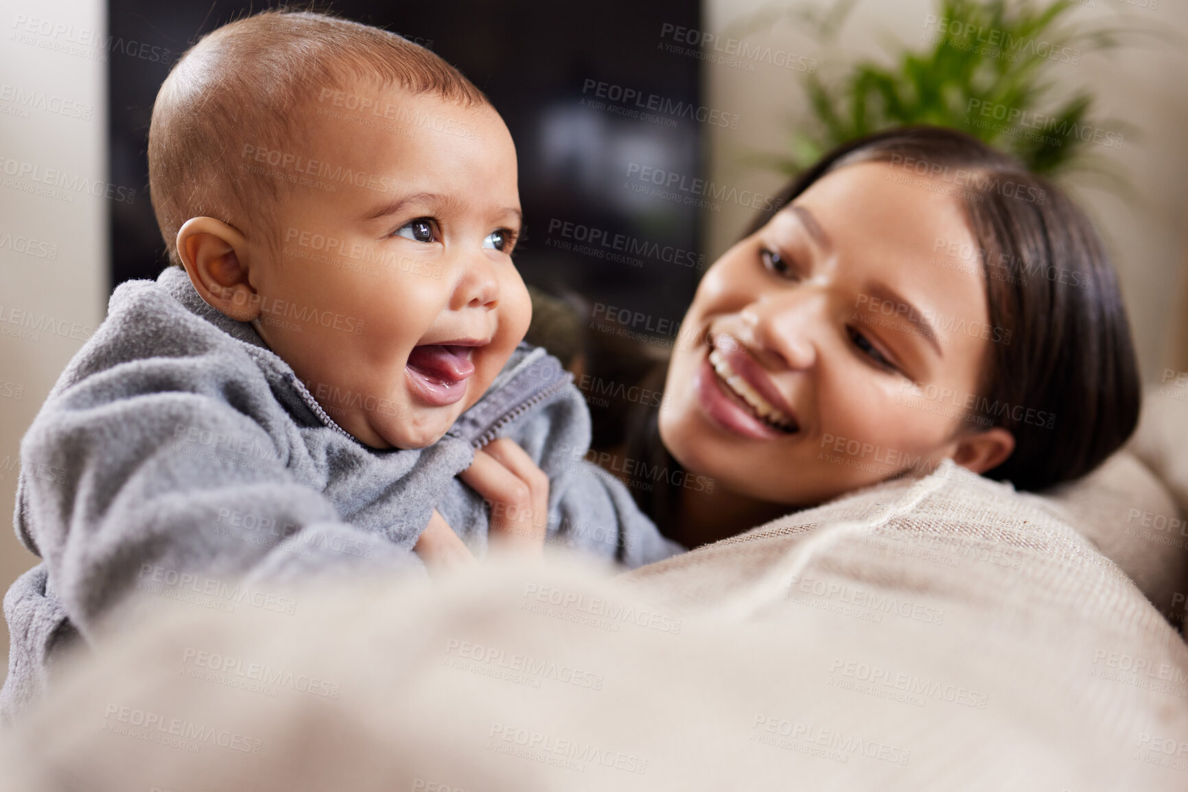 Buy stock photo Shot of a young woman relaxing with her adorable baby on the sofa at home