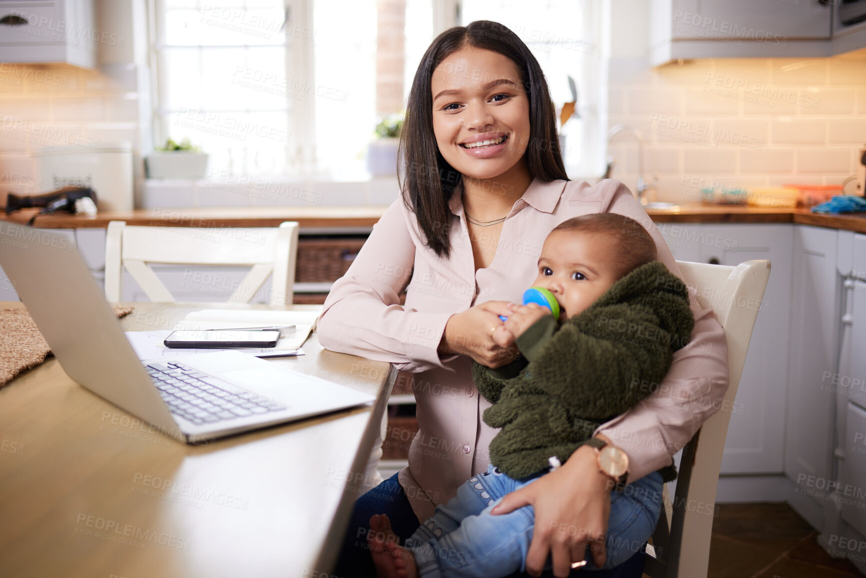 Buy stock photo Shot of a young woman using a laptop while caring for her adorable baby at home