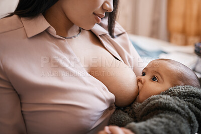 Buy stock photo Shot of a young woman breastfeeding her adorable baby on the sofa at home