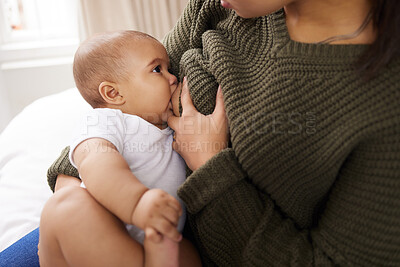 Buy stock photo Shot of a young woman breastfeeding her adorable baby on the sofa at home