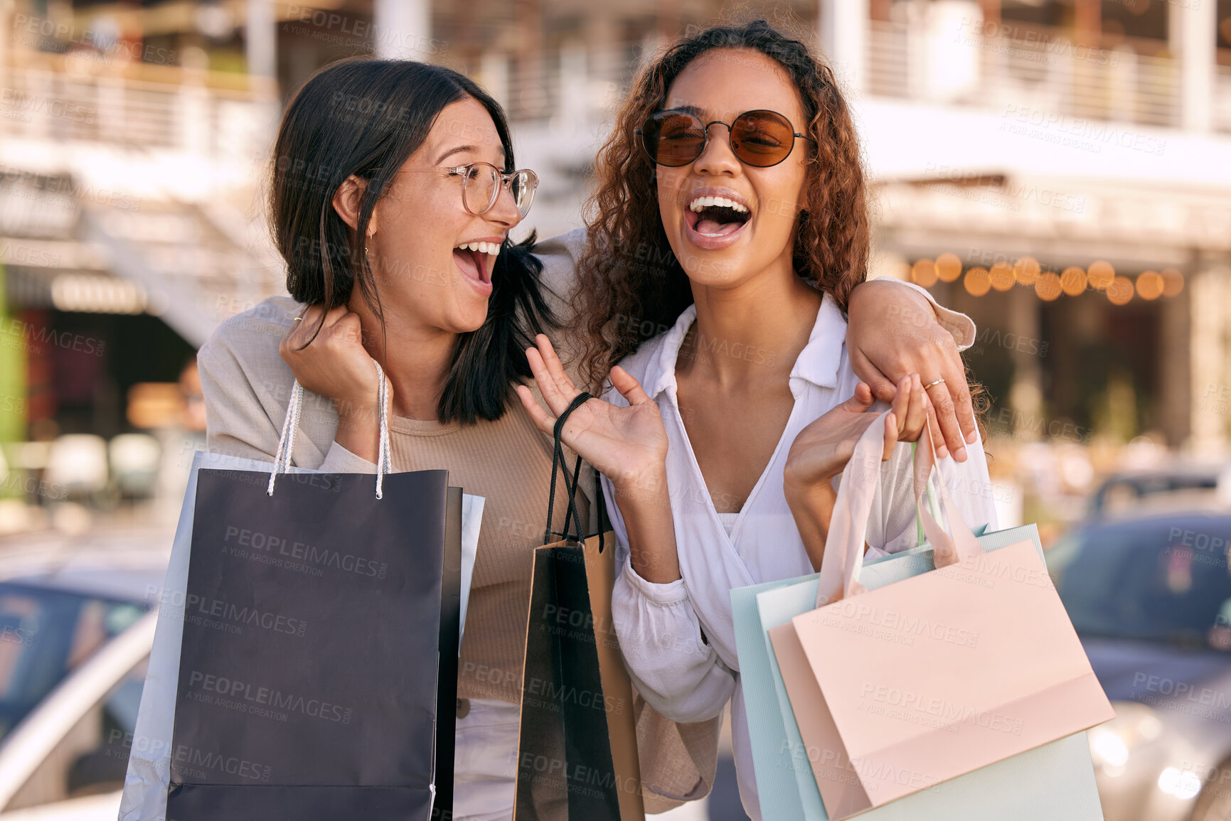 Buy stock photo Shot of two attractive young women standing outside together and bonding while shopping in the city