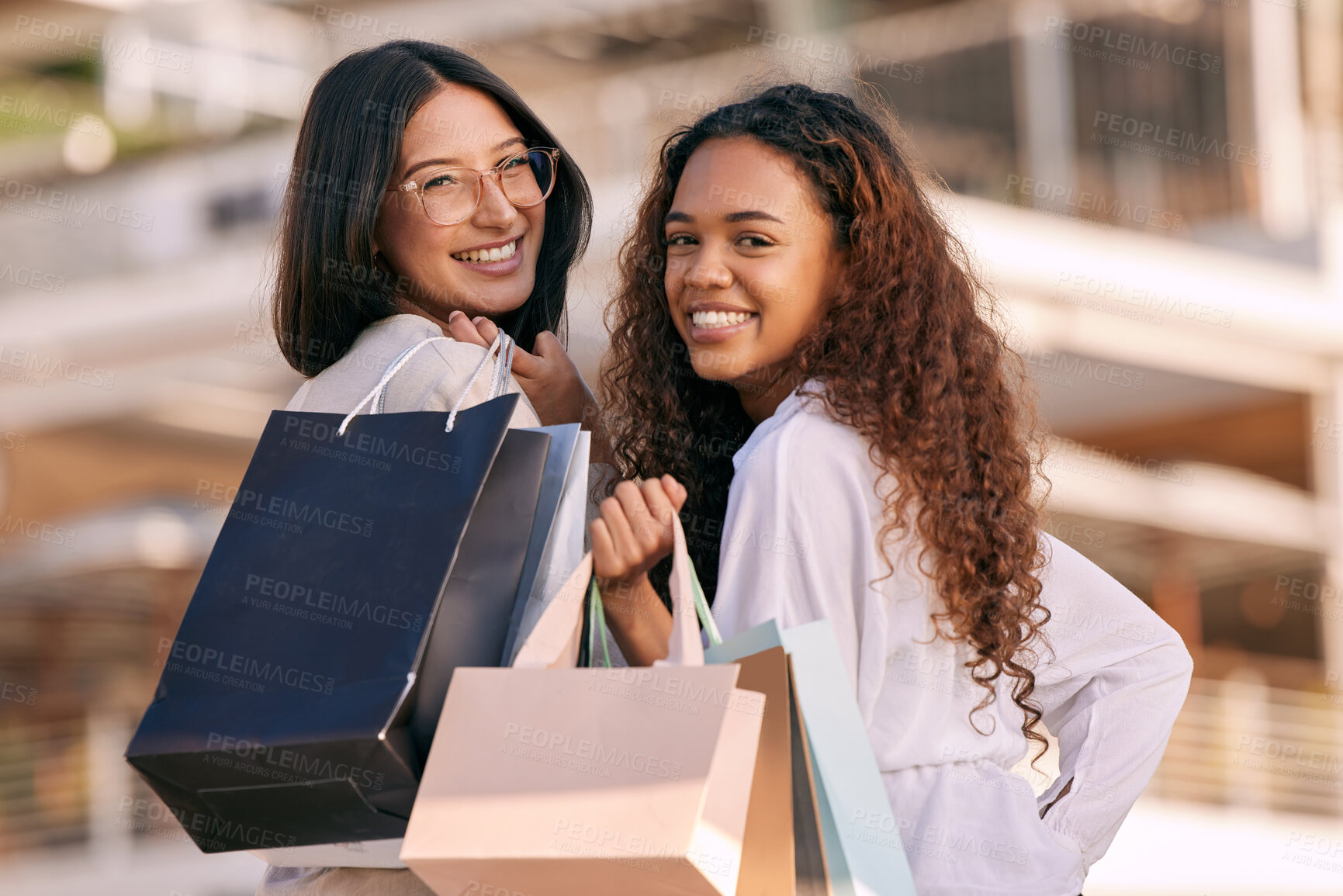 Buy stock photo Shot of two attractive young women standing outside together and bonding while shopping in the city