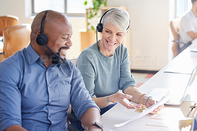 Buy stock photo Shot of two mature businesspeople going through paperwork together while working in a call centre