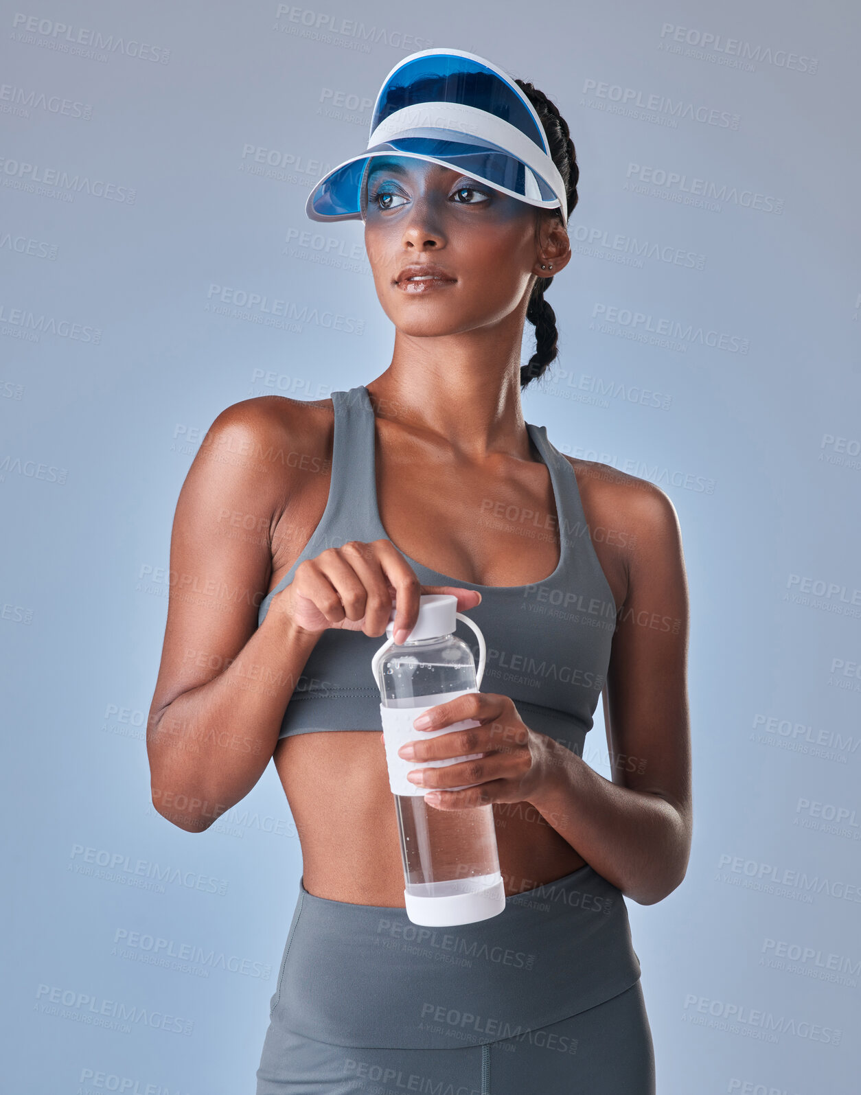 Buy stock photo Studio shot of a fit young woman drinking bottled water against a grey background