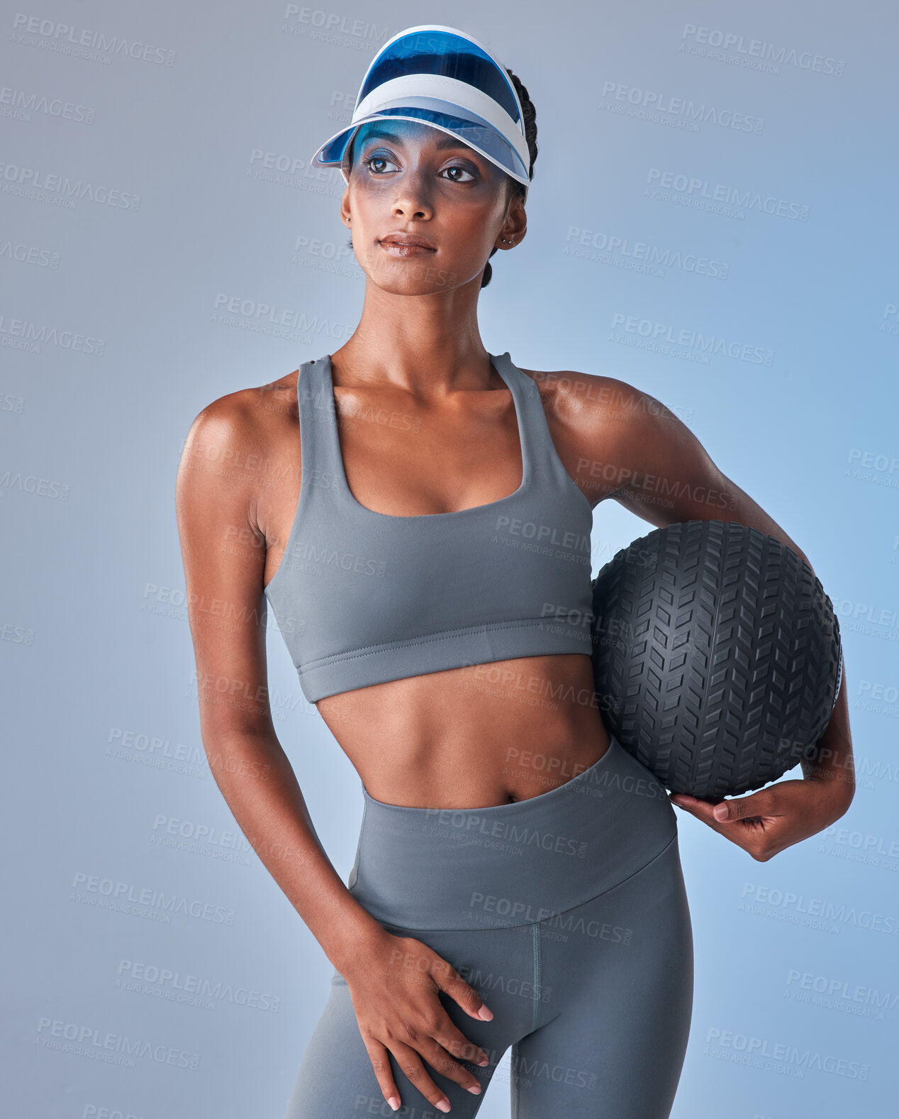 Buy stock photo Studio shot of a fit young woman working out with a medicine ball against a grey background