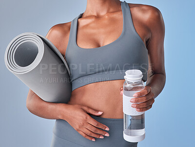 Buy stock photo Studio shot of a fit woman drinking bottled water against a grey background
