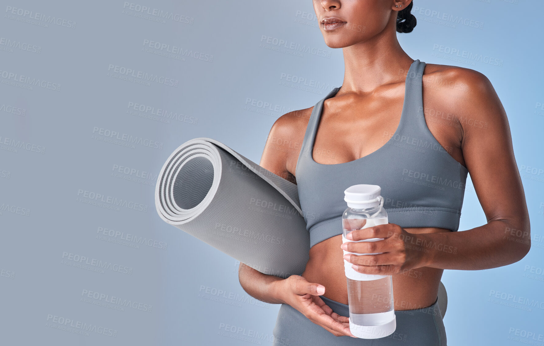 Buy stock photo Studio shot of a fit woman drinking bottled water against a grey background