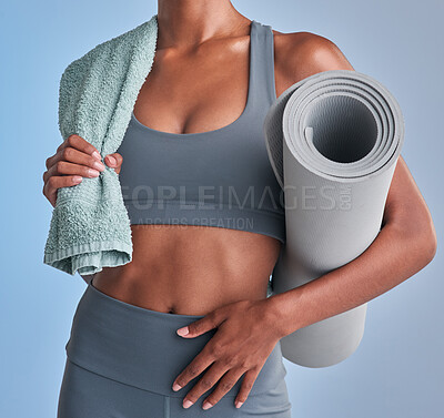 Buy stock photo Studio shot of a fit woman holding a towel and exercise mat against a grey background